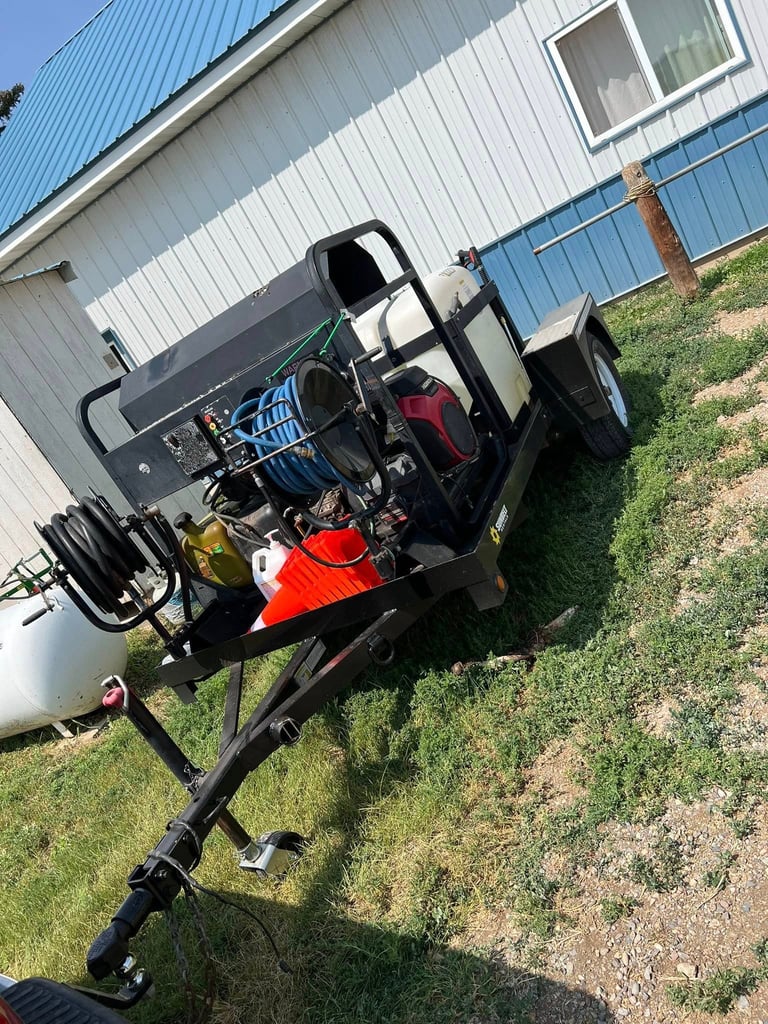 Custom-built dragster with red and black engine mounted on trailer parked outside metal building