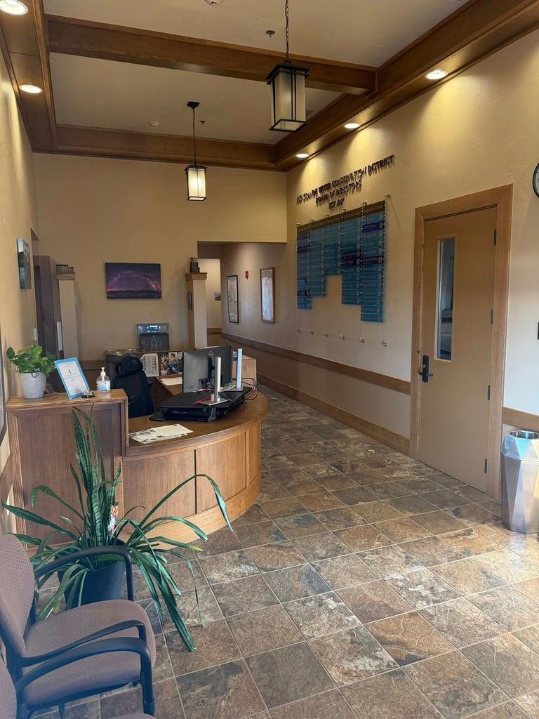 Modern medical office reception area with wooden desk, tile flooring, and waiting chairs near entrance doors